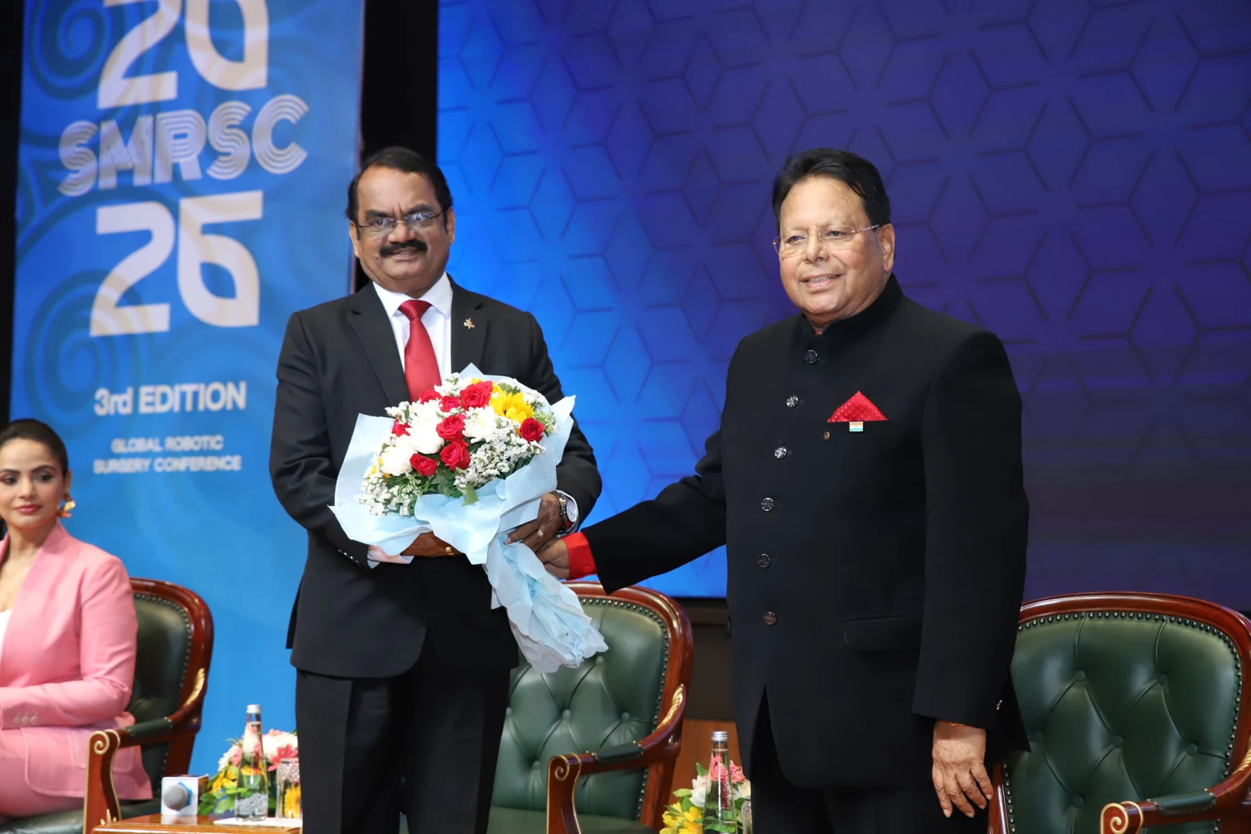 Participants standing together on a conference stage with a floral bouquet