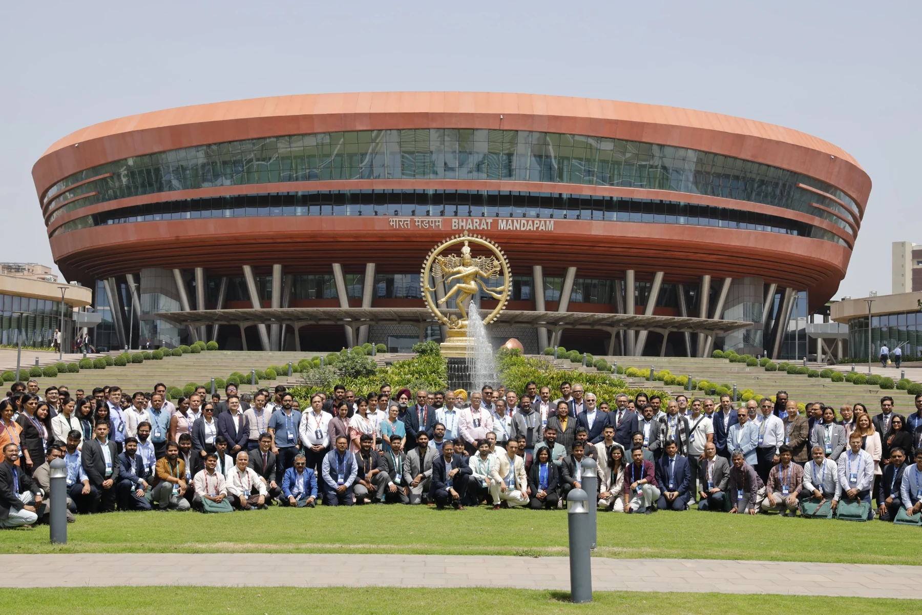 A large group assembled outdoors in front of a circular building